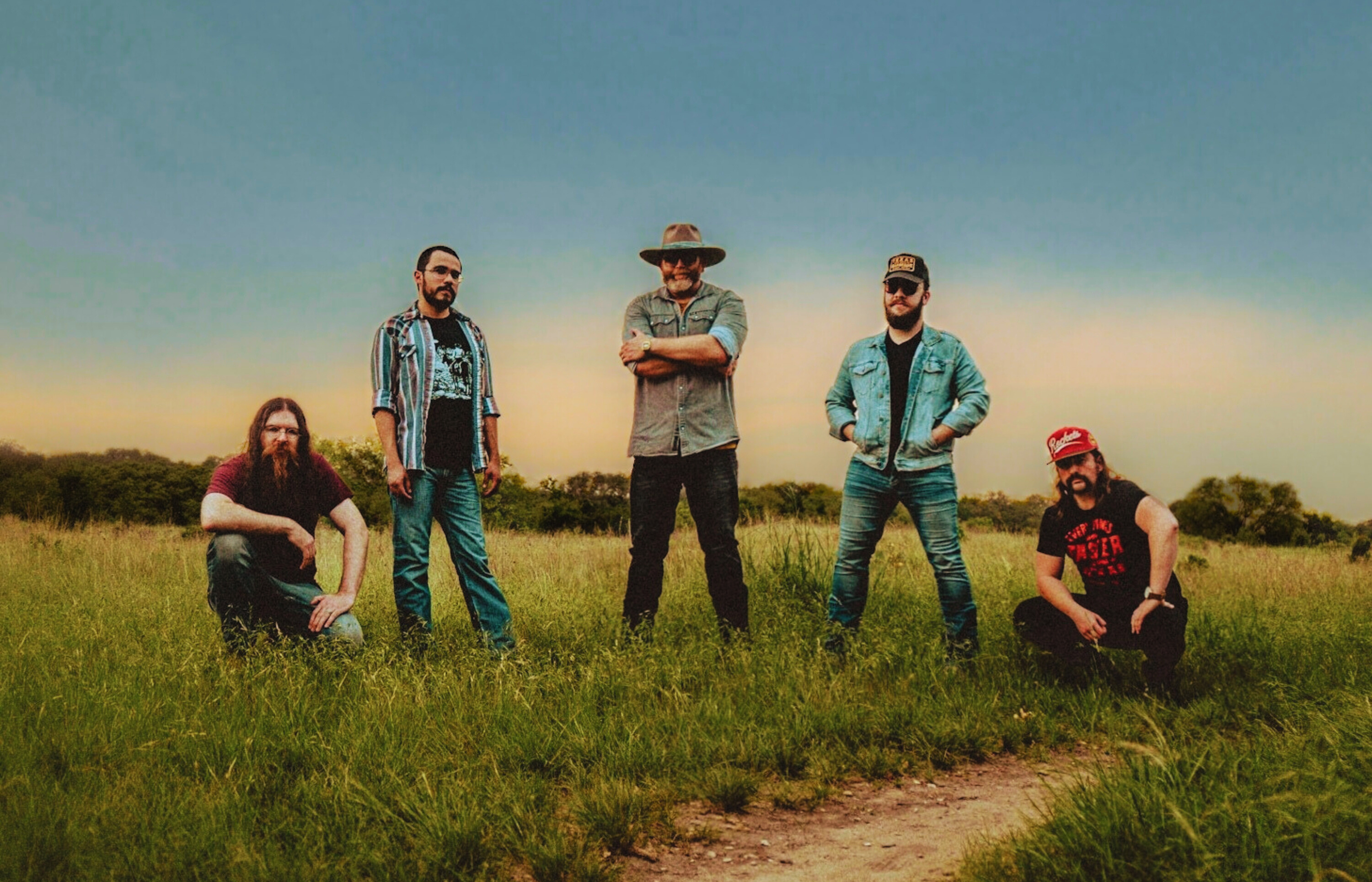 Band standing in open field, large open sky above